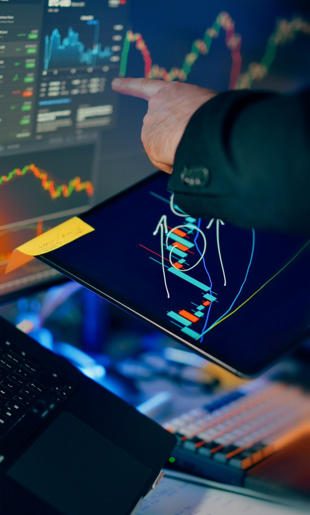 Financial trading workstation stock crypto investment analysis. Closeup hand pointing touchscreen displaying candlestick charts indicators price movement market volatility savings investing portfolio calculation smartphone tablet laptop monitors desktop finance technology night lighting focus strategy performance growth profit risk management economy currency blockchain